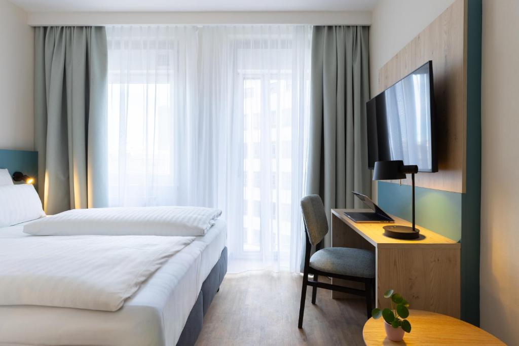 a hotel room with a bed and a desk and a television at Hotel Continental Frankfurt in Frankfurt