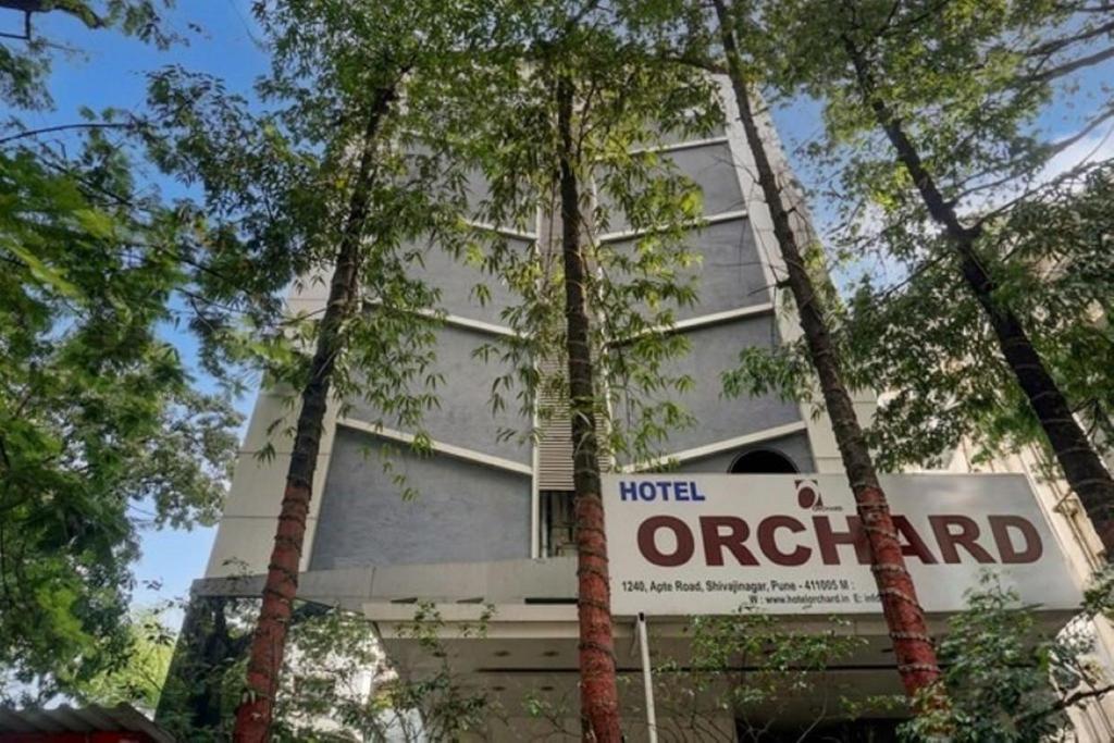 a hotel with a sign in front of a building at Hotel Orchard in Pune