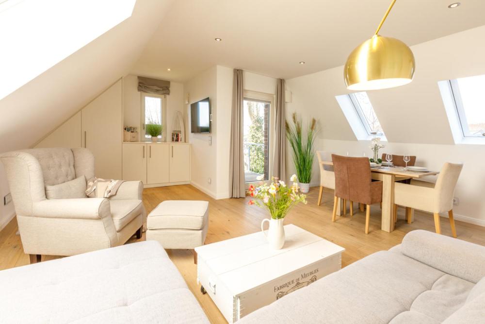 a living room with white furniture and a dining room at Himmelreich in Westerland
