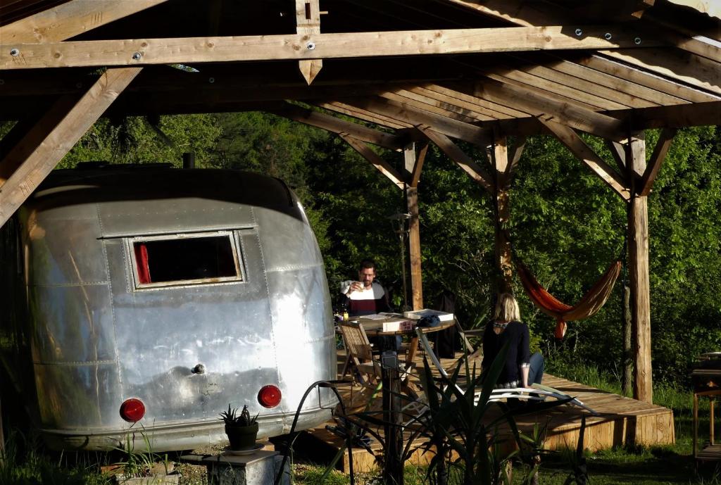 a man and woman sitting at a table in front of a trailer at Belrepayre Airstream Camp in Manses