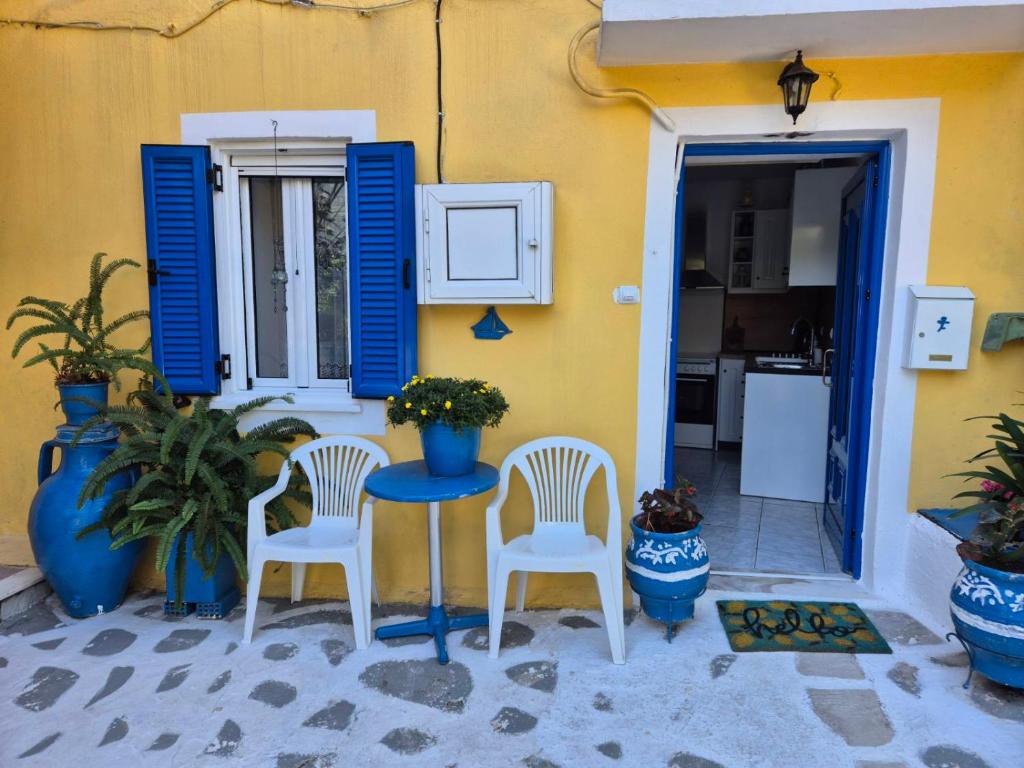a table and chairs in front of a house with blue shutters at Dimitra House in Parga