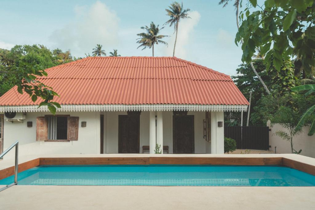 a house with a red roof and a swimming pool at Casa Mariposa in Ahangama