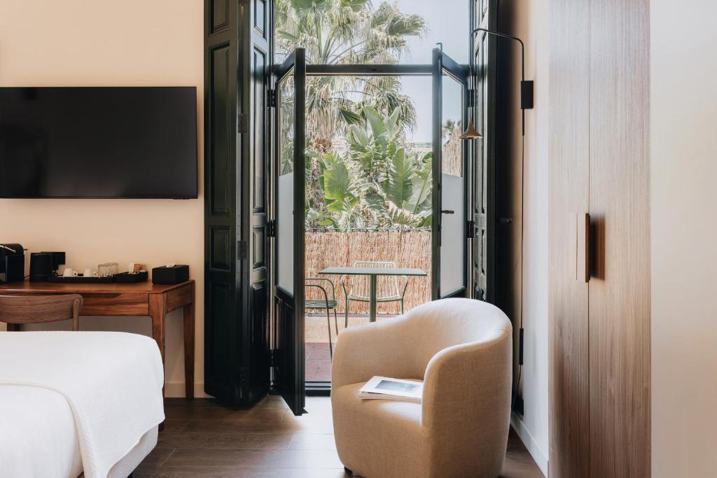 a bedroom with a bed and a chair and a table at La Chipirona Hotel in Valencia