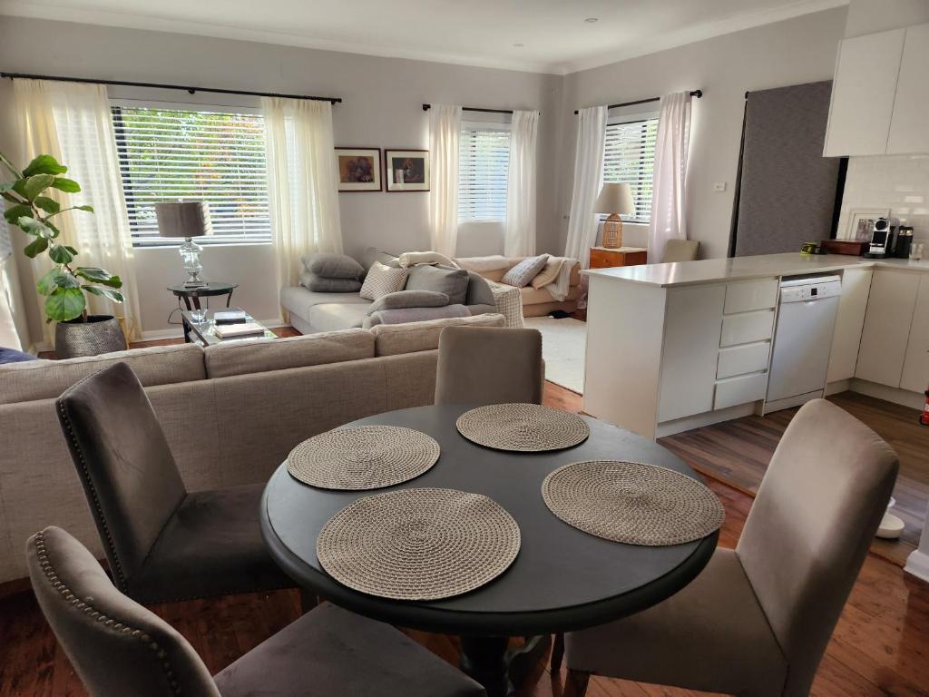 a living room with a table and a couch at Bowral Central Garden Apartment in Bowral