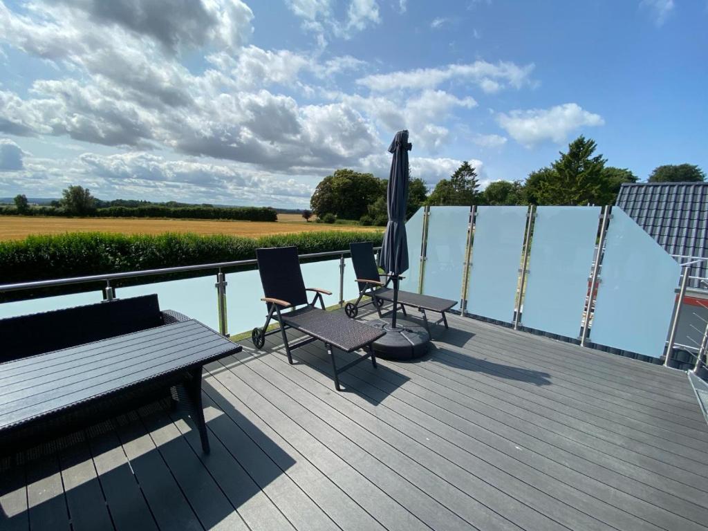 a wooden deck with two chairs and an umbrella at Haus Dani in Oldenburg in Holstein