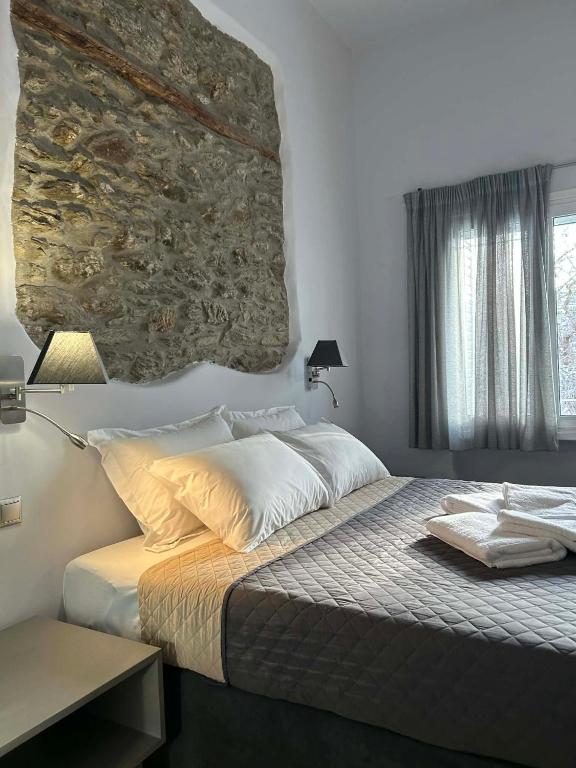 a bedroom with a bed with a stone wall at Amalize Luxury Apartments in Karistos
