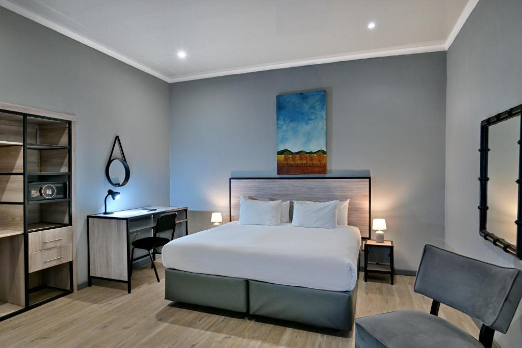 a bedroom with a bed and a desk and a computer at BON Hotel Rustenburg in Rustenburg