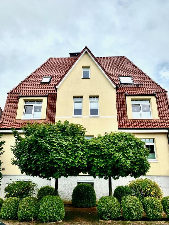 a yellow house with a red roof at Villa Topas in Wilhelmshaven