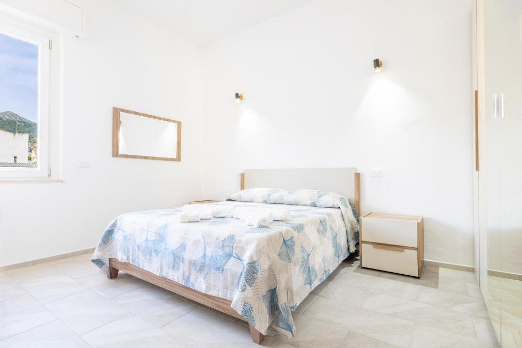 a white bedroom with a bed and a window at Ischera Apartments in Guspini
