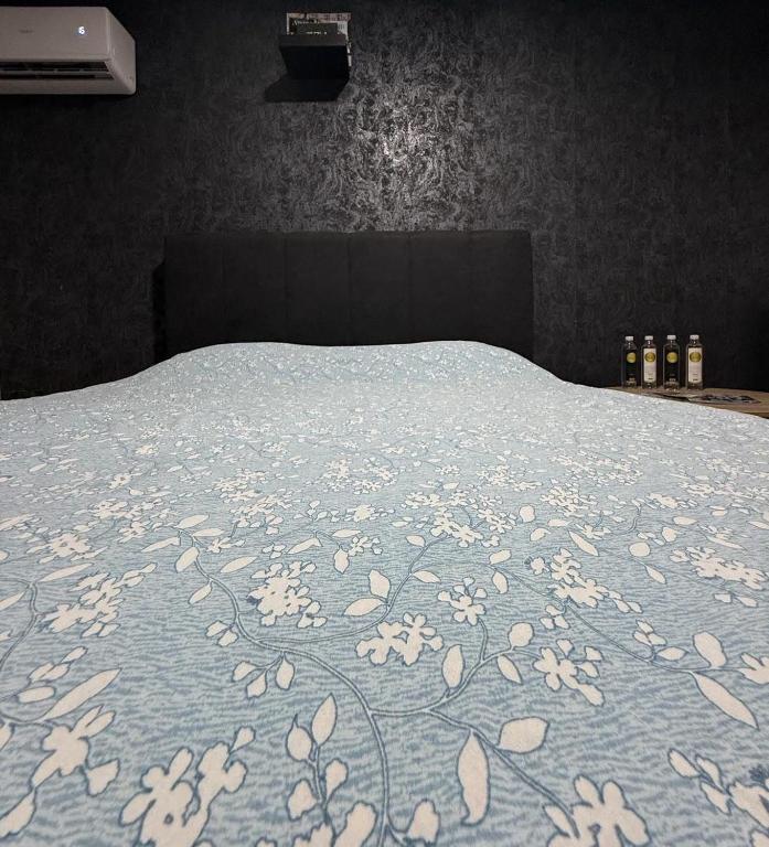 a bed with a blue blanket with flowers on it at Apartmani Benjamin in Tuzla