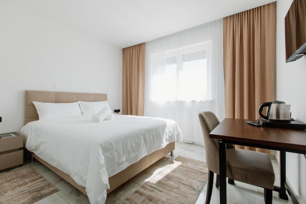 ein Schlafzimmer mit einem weißen Bett, einem Schreibtisch und einem Fenster in der Unterkunft Rustikana doo in Livno