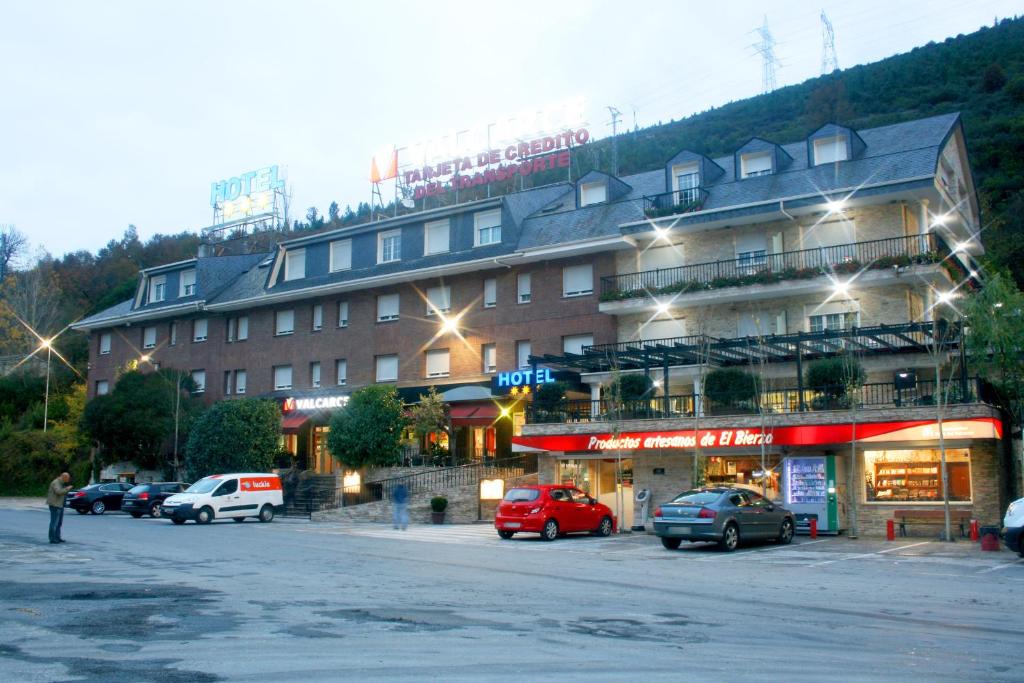 un gran edificio con coches estacionados en un estacionamiento en Hotel Valcarce Camino de Santiago en La Portela de Valcarce