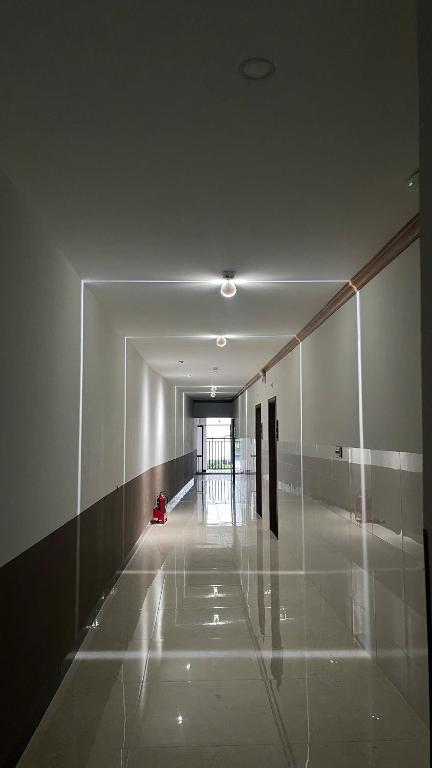 a hallway of a building with a person sitting on the floor at Khách Sạn Phượng Vĩ in Cà Mau