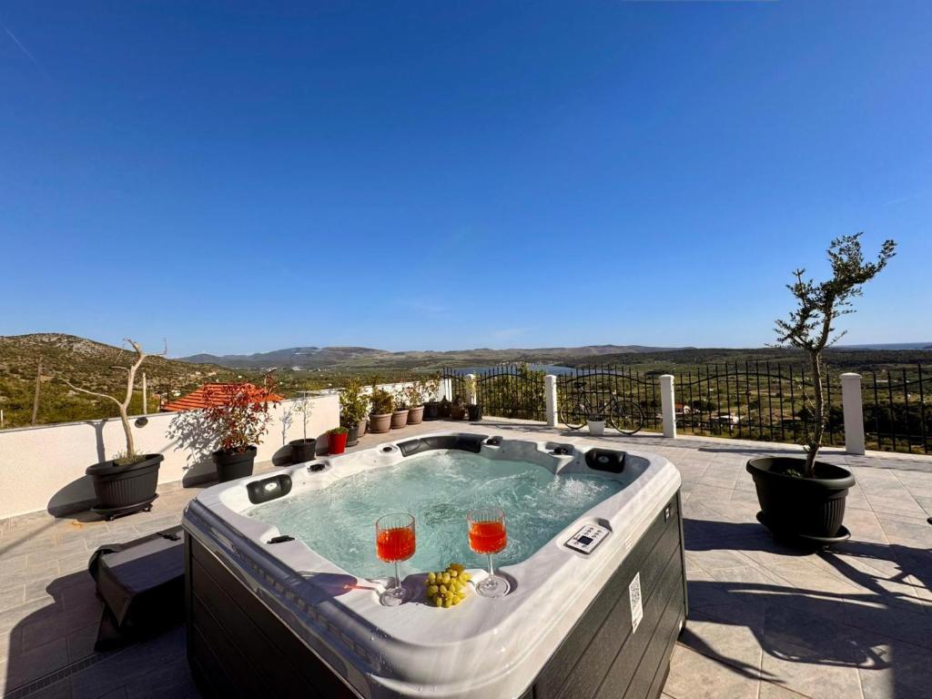 a hot tub on a patio with drinks in it at Vranac Country house Šibenik in Donje Polje