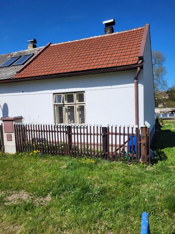 a white house with a fence in the grass at Domek U hřiště in Hlinsko