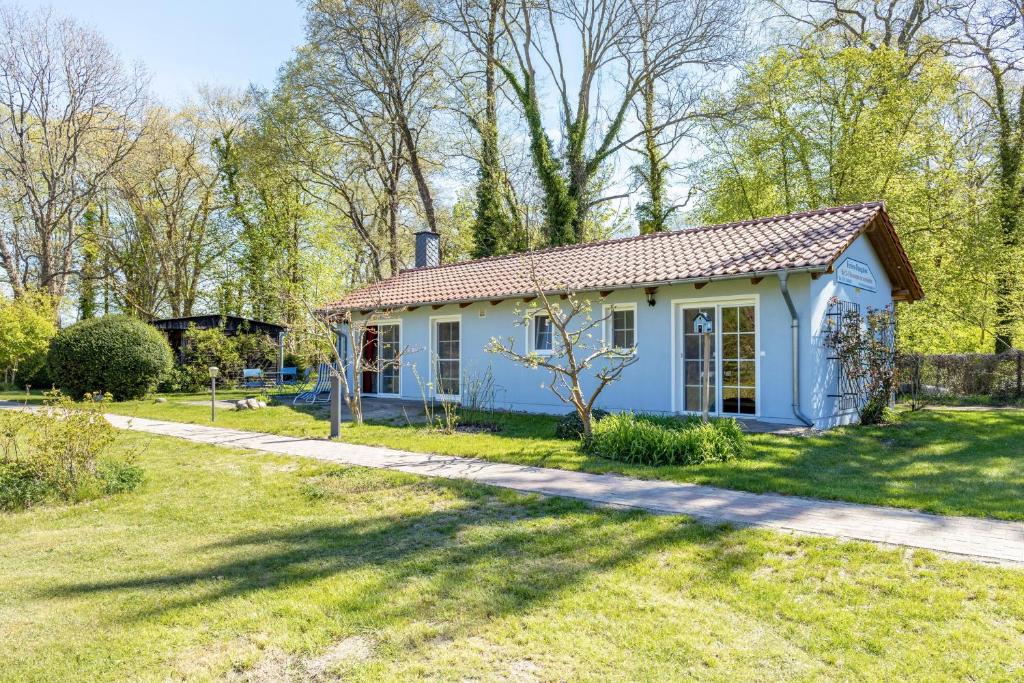 a small blue house in a yard at Bungalow am Haussee in Himmelpfort