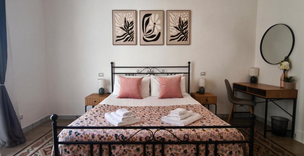 a bedroom with a bed with pink pillows and a desk at Dimora Tarantina in Taranto