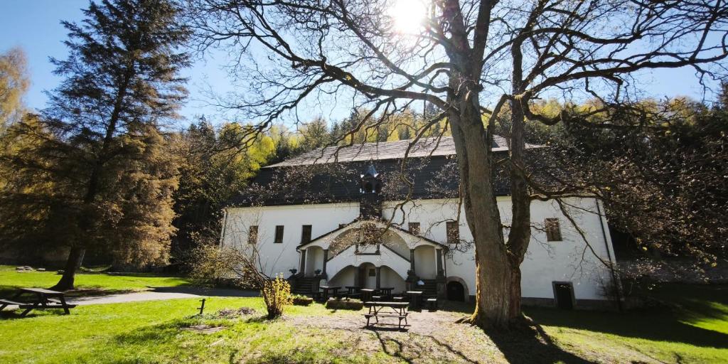 a large white building with a tree in front of it at Zámeček Bischofstein in Teplice nad Metují