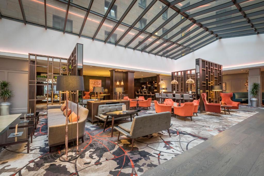 een lobby van een hotel met stoelen en tafels bij Clayton Hotel Leopardstown in Leopardstown