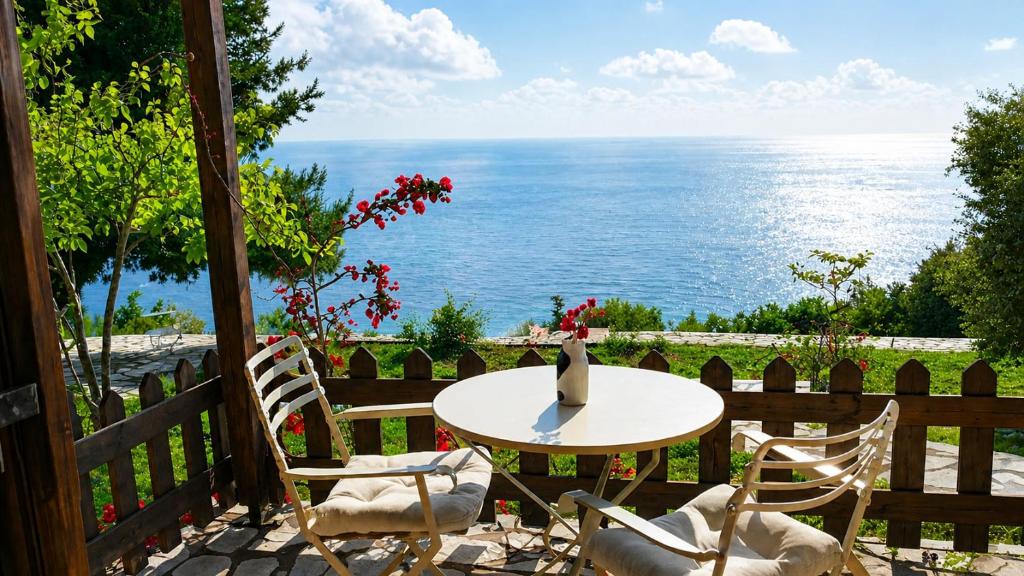 a table and chairs on a patio with a view of the ocean at Anerada Houses - Seaviews Above Egremni in Lefkada in Athani