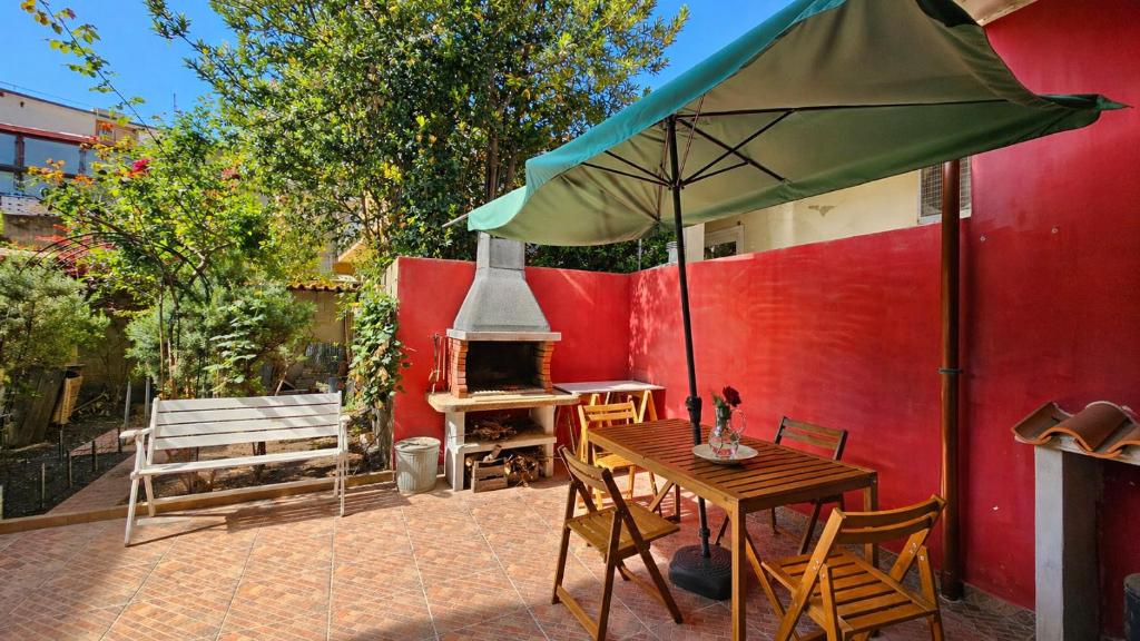 a patio with a table and an umbrella and a fireplace at Casa Are in Oristano