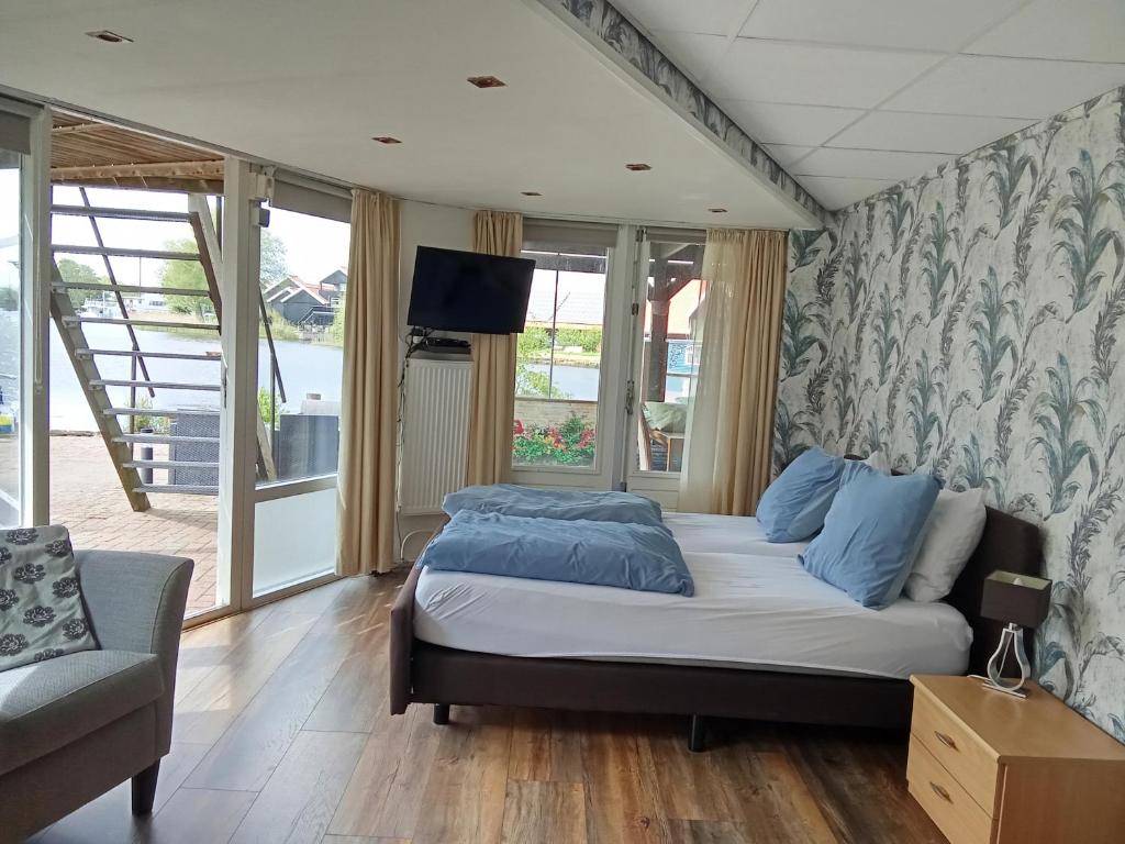 a bedroom with a bed and a couch and windows at B&B aan het water in Earnewâld