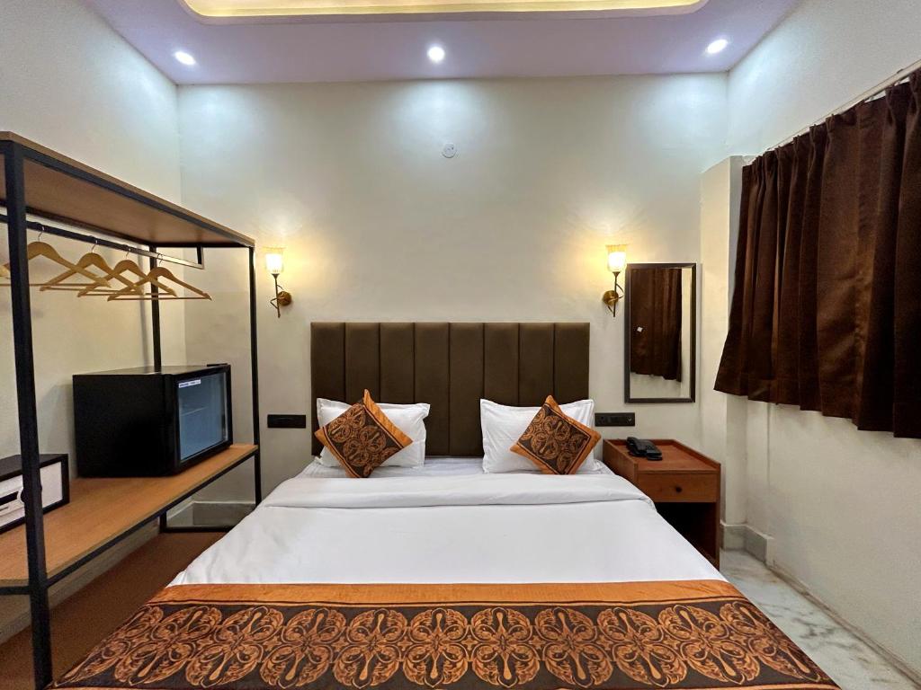 a bedroom with a large bed and a television at Hotel CozyKey Rajpur Road in Dehradun