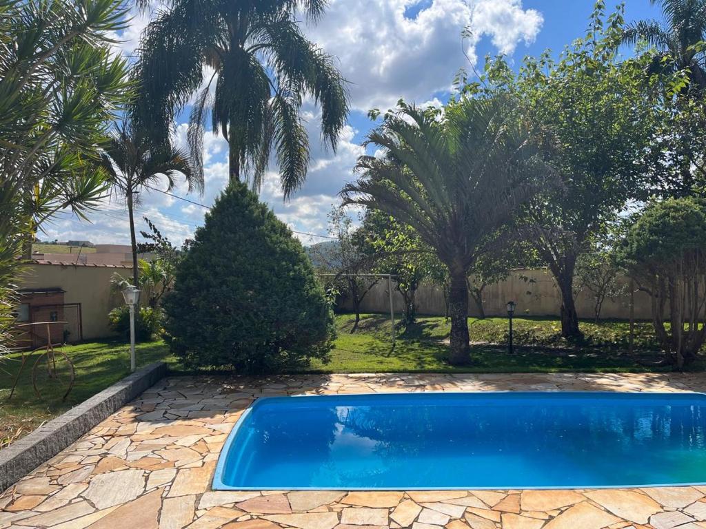 a swimming pool in a yard with palm trees at Chácara com Piscina in Poços de Caldas