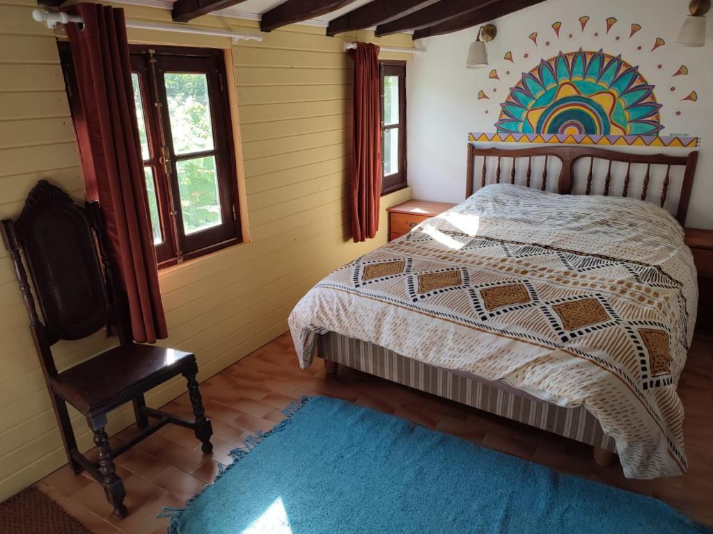 a bedroom with a bed and a chair and a blue rug at Bota Rota Pilgrim House in Paredes de Coura