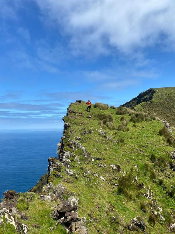 a person riding a bike on a hill near the ocean at Casa do Henri in Corvo