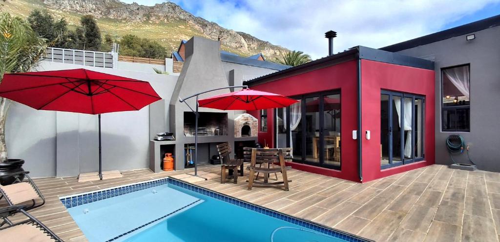 a house with a swimming pool and two red umbrellas at Getaway between the sea and the mountains in Gordonʼs Bay