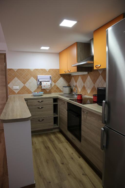 a kitchen with wooden cabinets and a stainless steel refrigerator at Apartment Alana in Podvelka