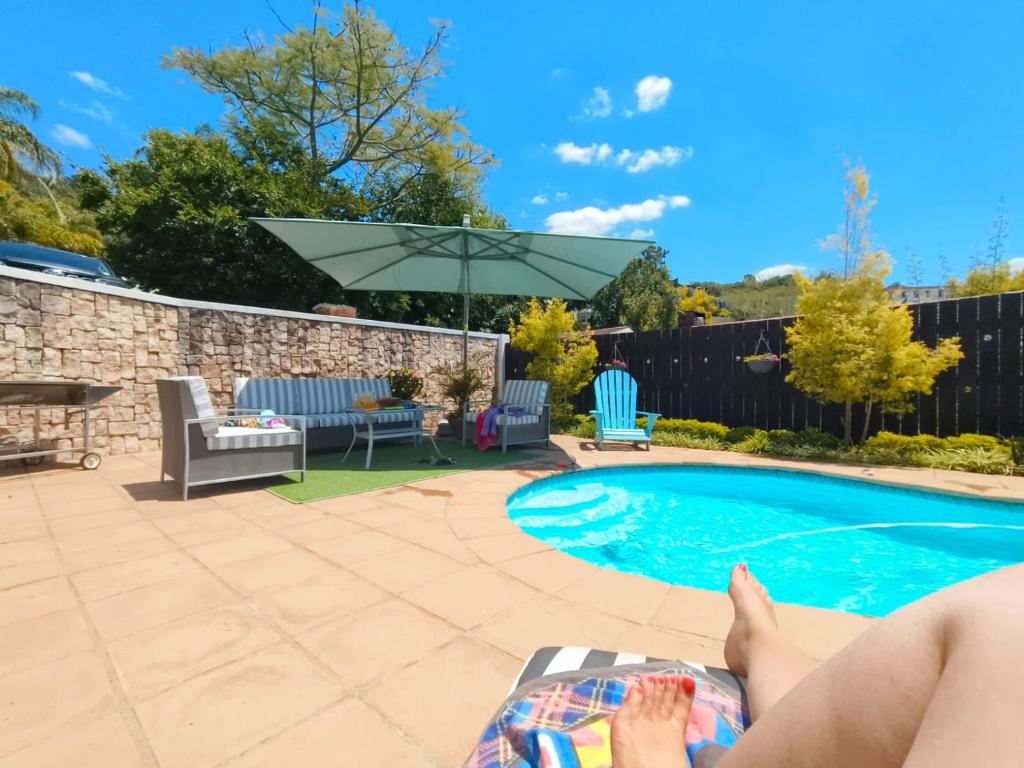 a person laying on a chaise lounge next to a swimming pool at Berg and Dal in Paarl