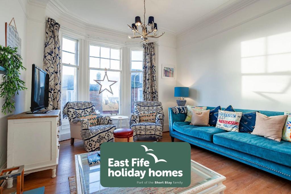 a living room with a blue couch and a tv at Overton - Elie in Elie