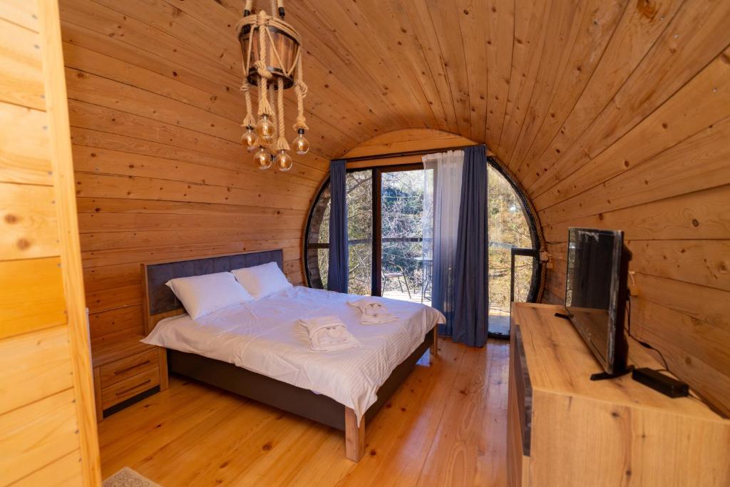 a bedroom in a log cabin with a bed and a tv at Cottages Chateau Ochia in Koromkhet'i