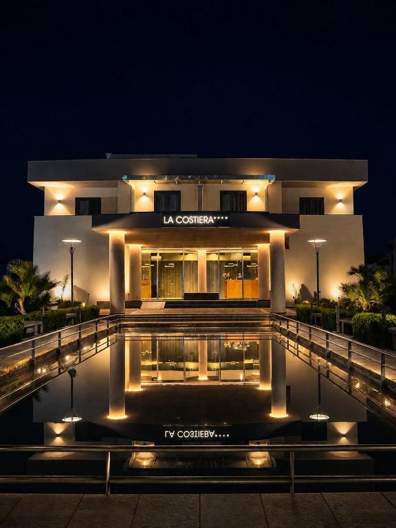 a building with a pool in front of it at night at Hotel La Costiera in Varcaturo