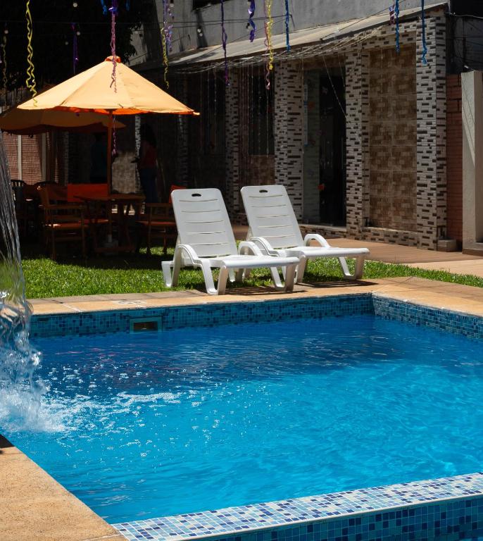 two chairs and an umbrella next to a swimming pool at Hotel Ullanka in Encarnación