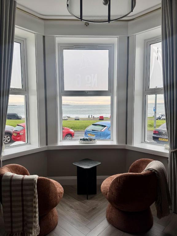 a living room with three windows and two chairs at No 6 Lansdowne in Portrush