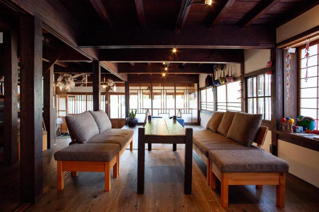 a living room with couches and a table and windows at Guest House Maru in Kashima