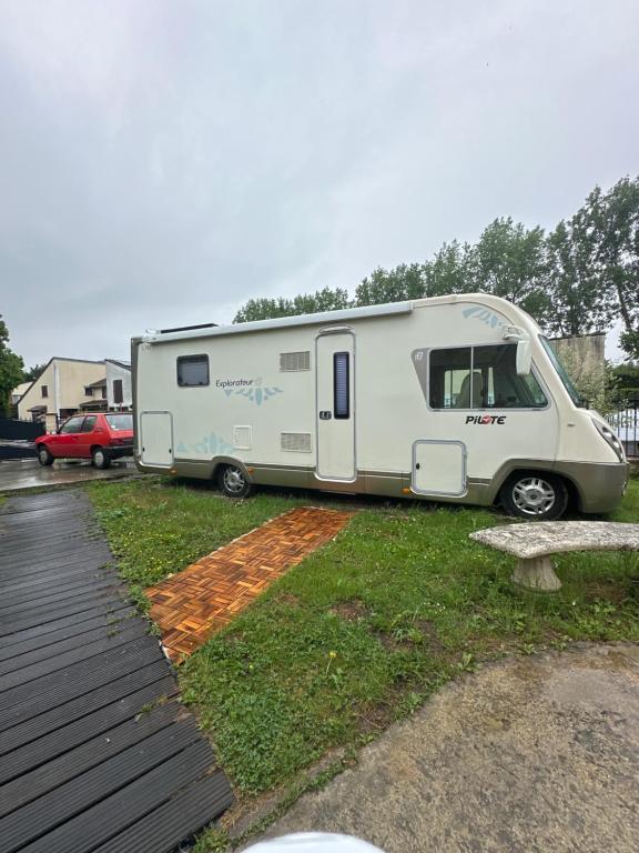 a white trailer parked in a grass field at Camping car Paris in Savigny-le-Temple