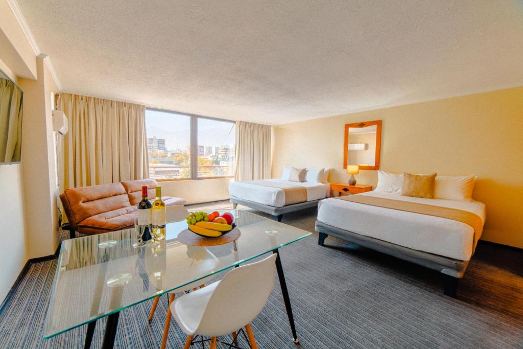 a hotel room with two beds and a glass table at Hotel Casa Nogales in Santiago