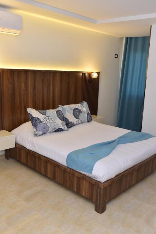 a bedroom with a large bed with a wooden headboard at Impavid Hotel in Gabès