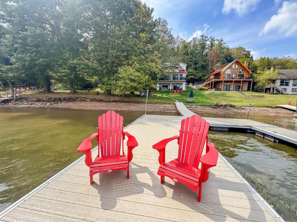 two red chairs sitting on a dock near the water at New Luxury Lakefront Walk to Wisp in McHenry