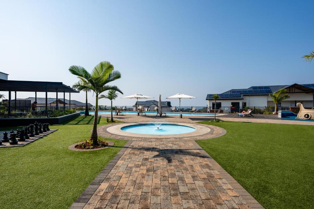 a swimming pool in a park with a palm tree at Ballito Hills 369 in Ballito