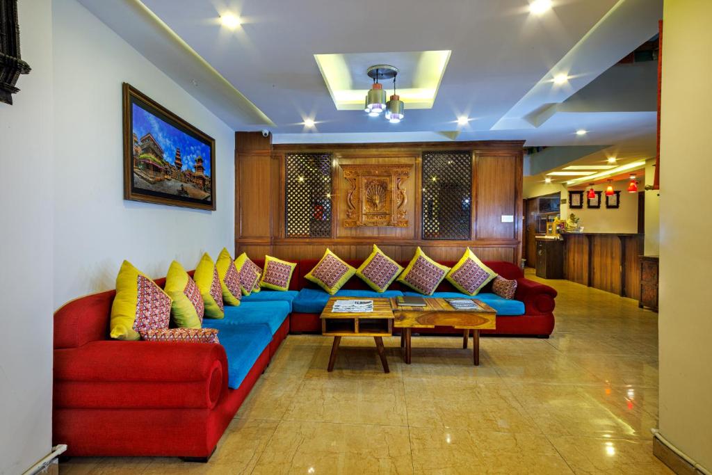 ein Wohnzimmer mit einem roten Sofa und bunten Kissen in der Unterkunft Hotel Central Prime in Kathmandu