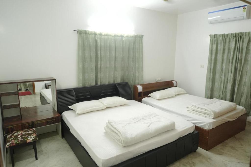 a bedroom with two beds and a dresser and a mirror at Pulimada Stays in Trichūr