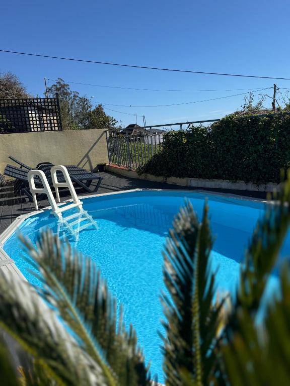 a swimming pool with two chairs in a yard at Casa do terno com piscina in Arco da Calheta