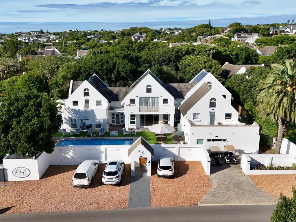 a large white house with cars parked in front of it at Adrift Guesthouse in St Francis Bay