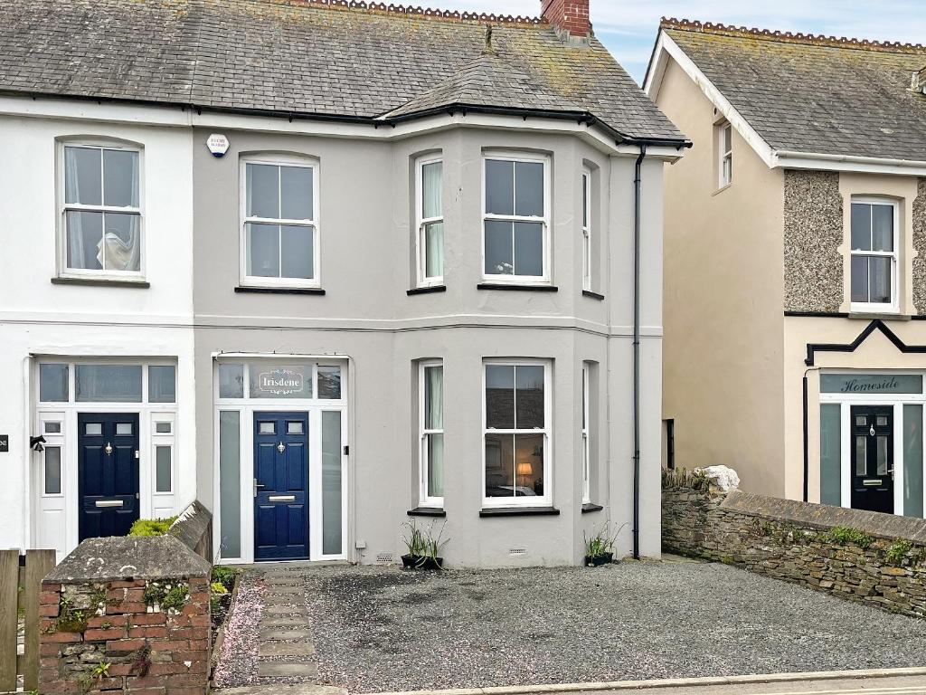 a white house with blue doors on a street at Irisdene in Tintagel
