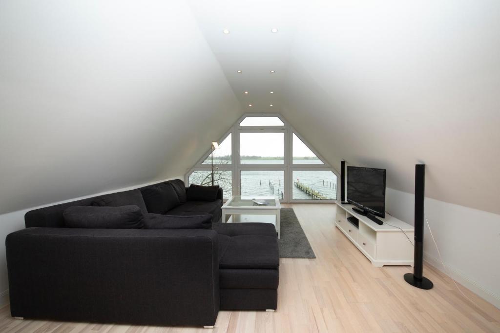 a living room with a black couch and a tv at Schleitraum Appartement in Rabenkirchen-Faulück
